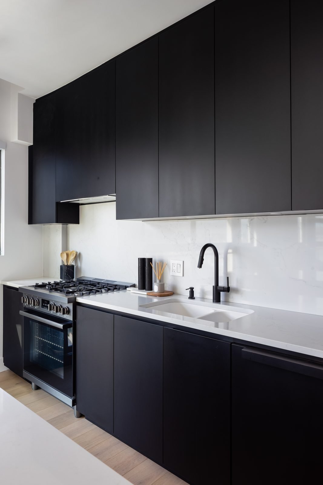 Matte black cabinets, quartz countertops and a stainless dual-fuel range in a Downtown Vancouver loft kitchen