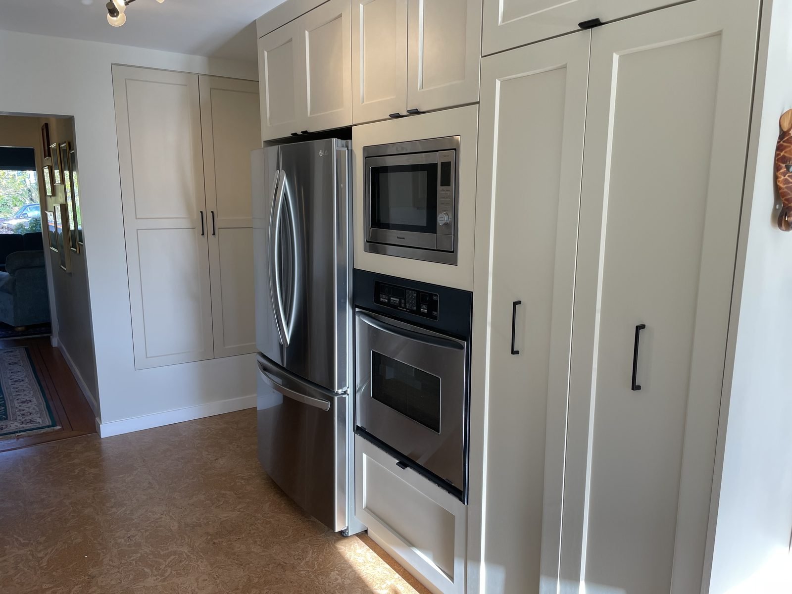 Stainless fridge, microwave and wall oven built into tall cream cabinets in a Dunbar, Vancouver kitchen