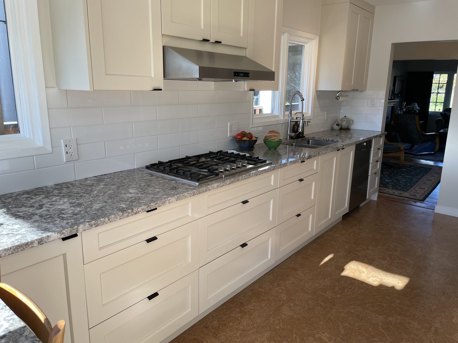 Full galley view with cork flooring, cream shaker cabinets and granite counters in a Dunbar, Vancouver kitchen