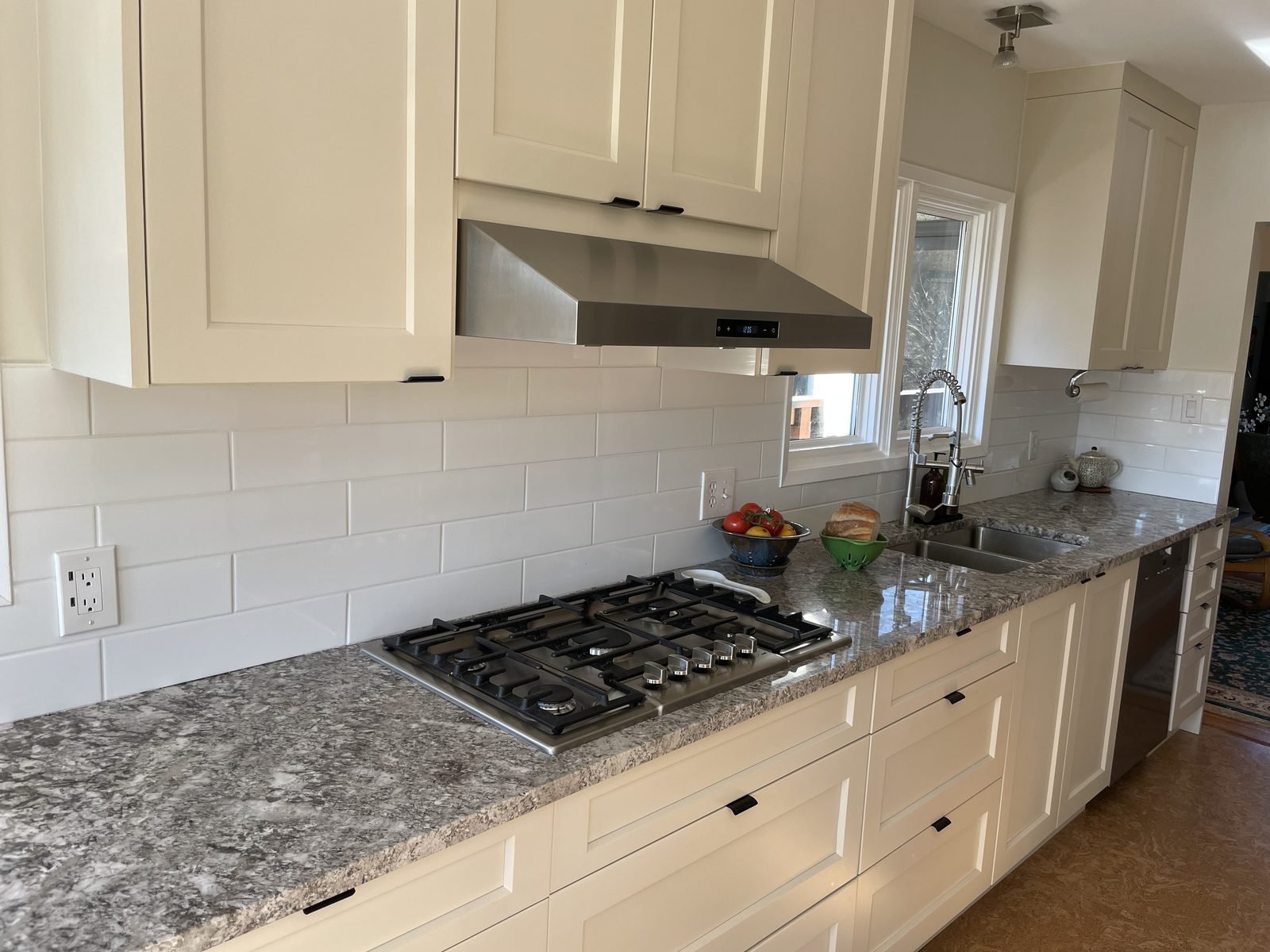 Dunbar kitchen with cream shaker cabinets, grey granite countertops, white subway tile and a gas cooktop