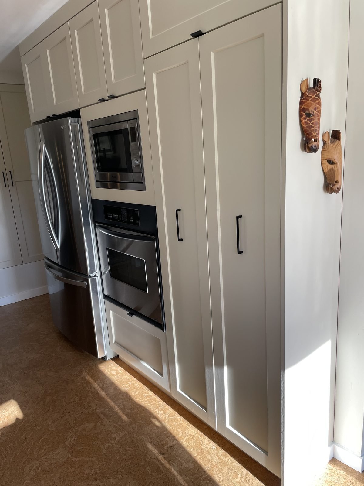 Tall panel-style pantry wall beside a stainless fridge, built-in microwave and wall oven in a Dunbar kitchen renovation
