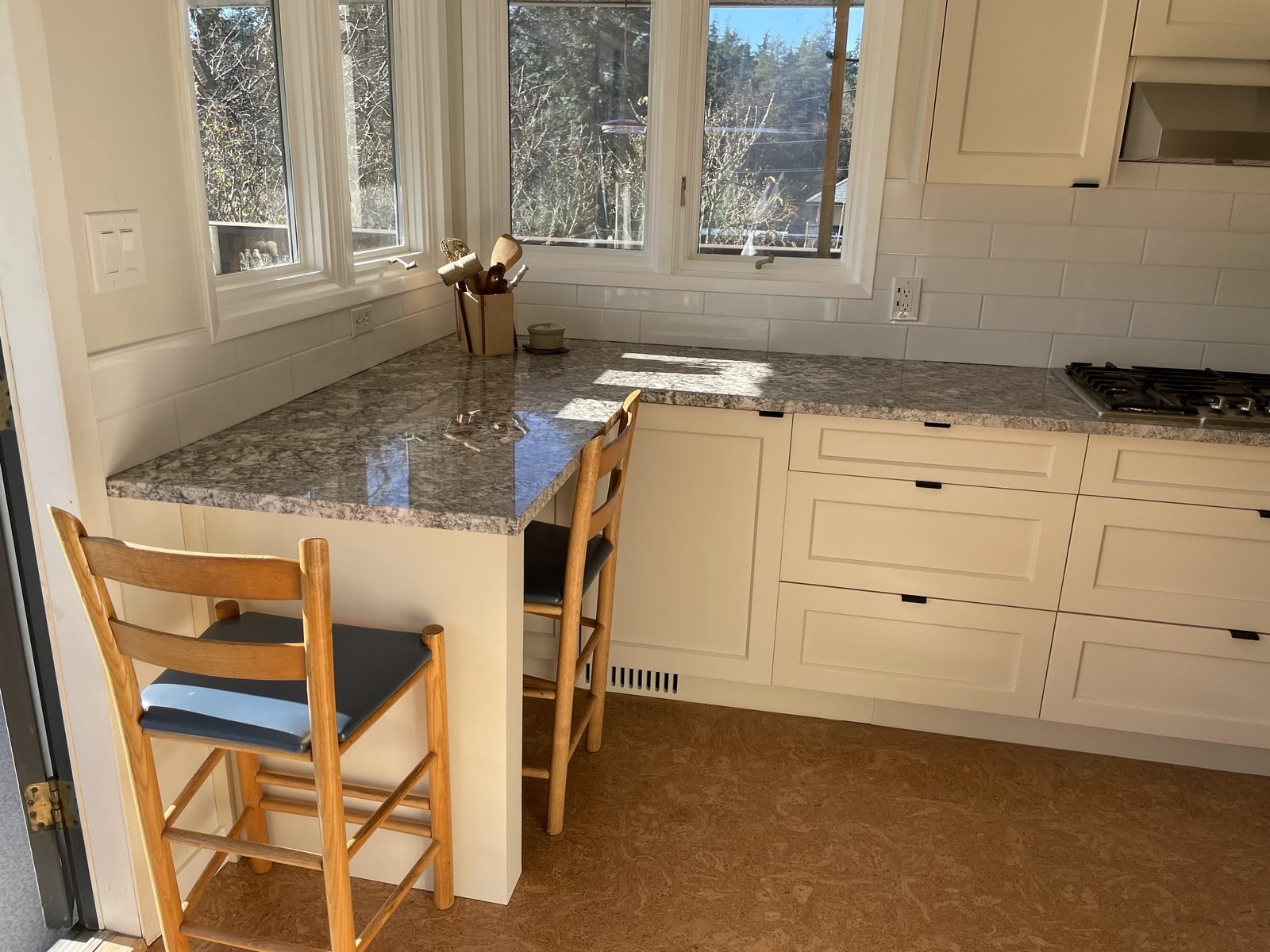 Granite breakfast bar with seating by the corner windows in a renovated Dunbar kitchen