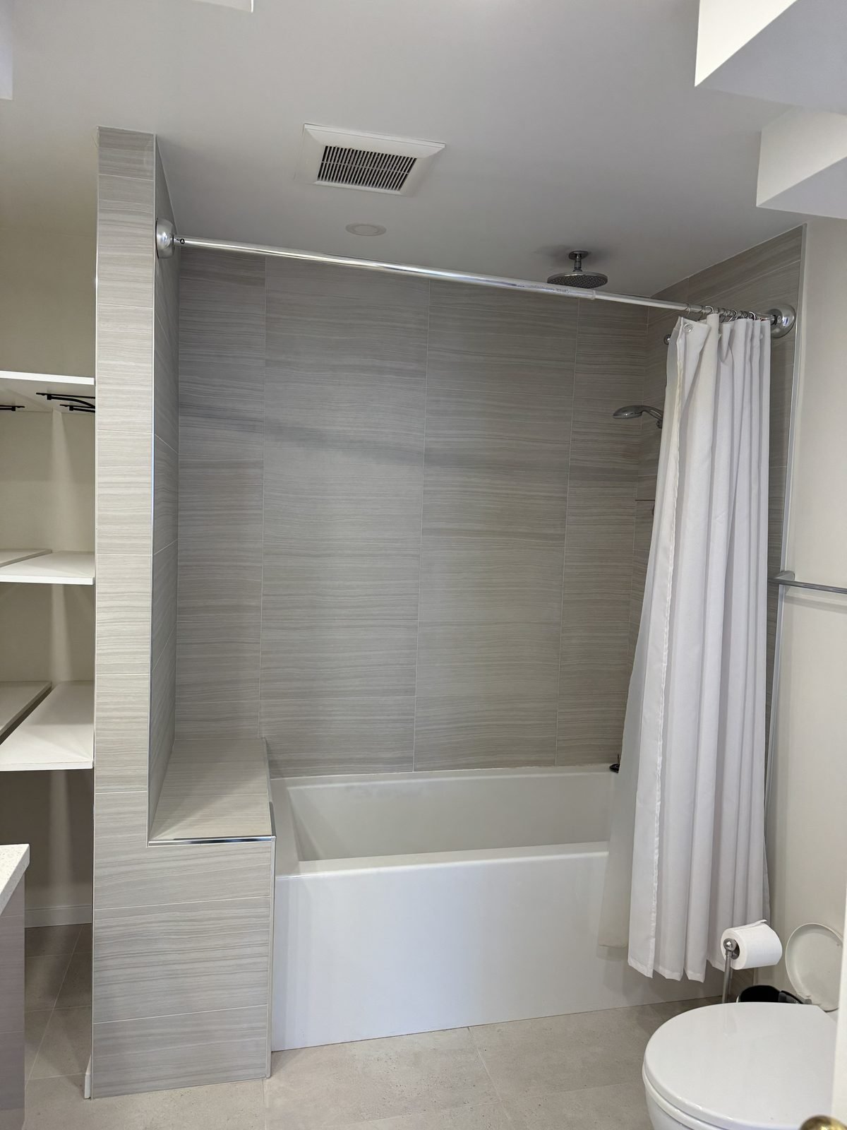 Before: original tub with a shower curtain and tiled surround in a Fairview condo ensuite