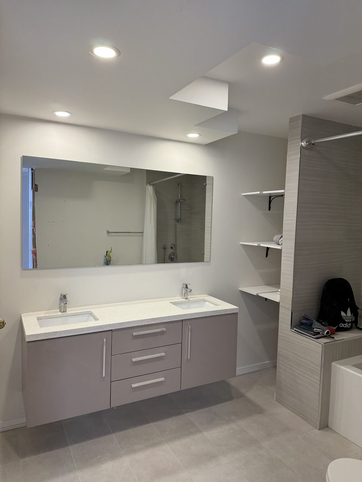 Before: original grey floating vanity and frameless mirror in a Fairview condo ensuite