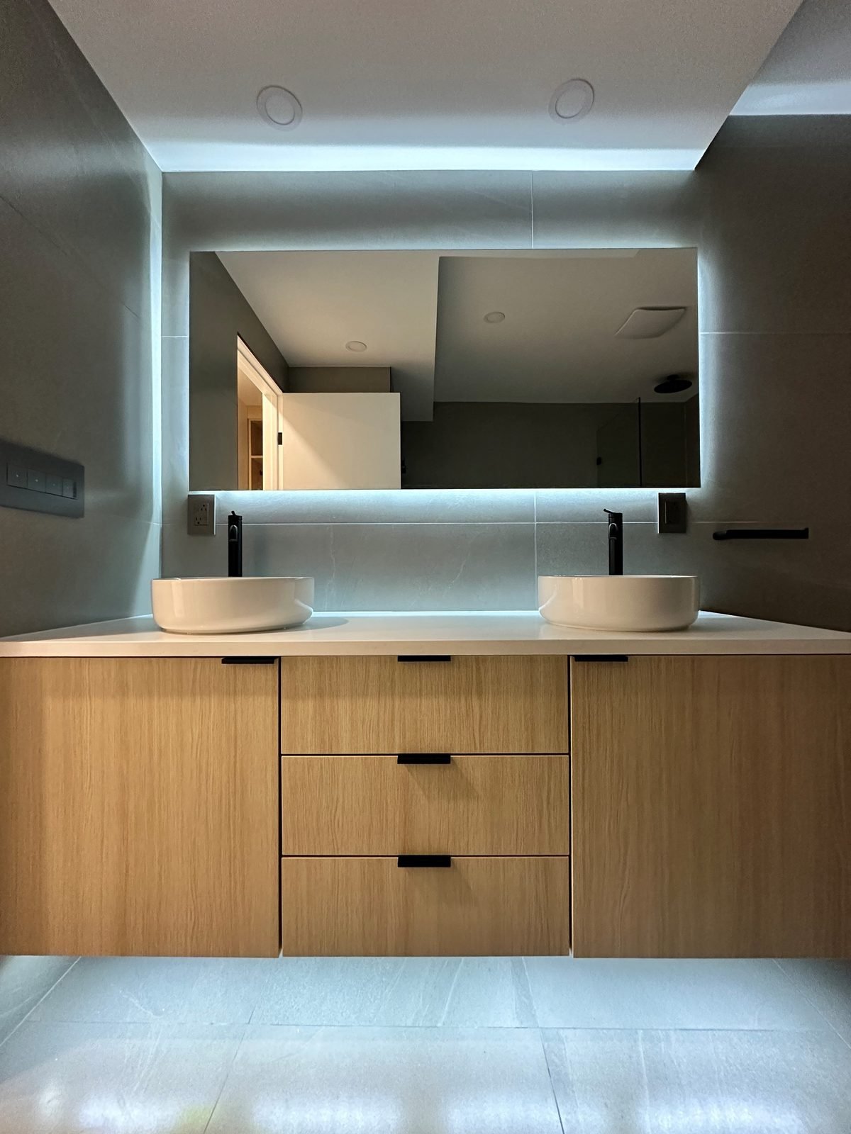 Renovated Fairview condo ensuite with a wood-grain double vanity and backlit mirror