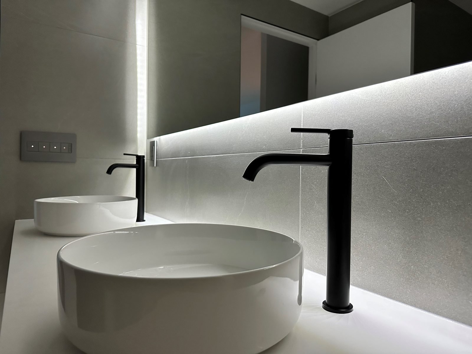Round vessel sinks with tall matte black faucets on a white quartz counter in a Fairview condo ensuite