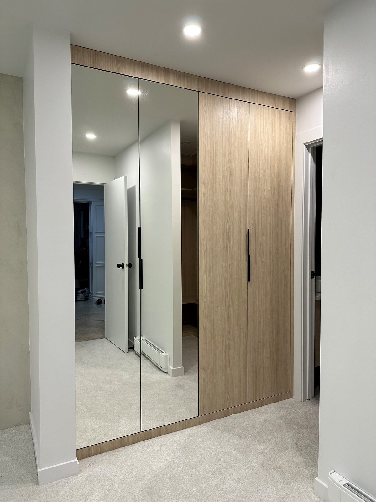 After: custom floor-to-ceiling built-in closet with mirrored and wood-grain doors in a Fairview condo primary bedroom