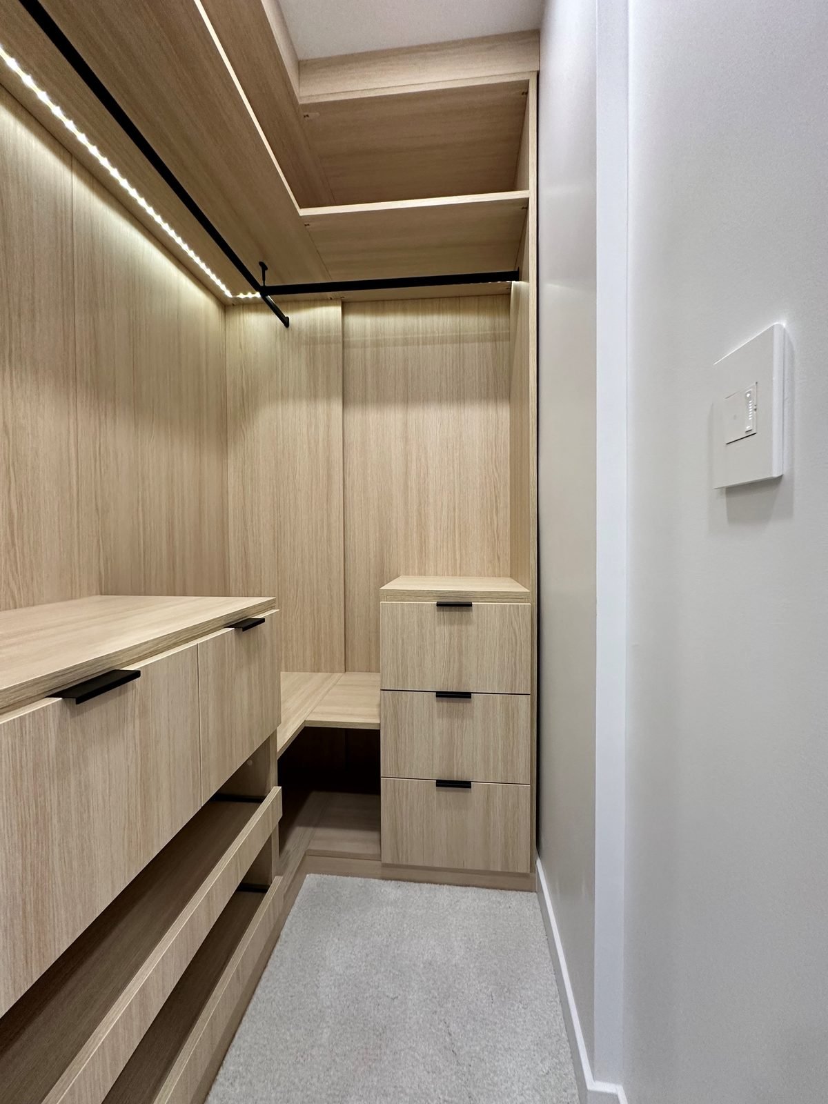 New walk-in closet with wood-grain shelving, drawers and LED strip lighting in a Fairview condo