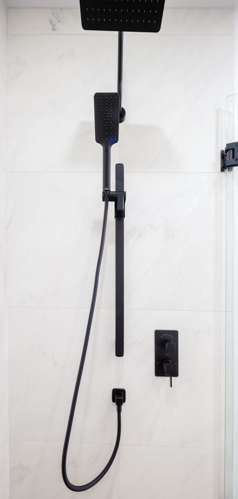 Matte black rain shower and hand shower on large-format white tile in a Gastown condo ensuite