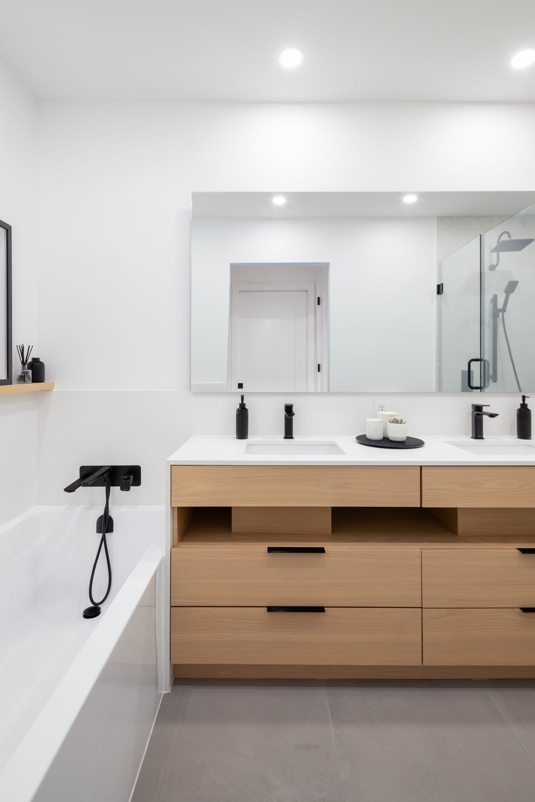 White oak floating double vanity with open shelves, quartz top and black faucets in a Gastown condo ensuite
