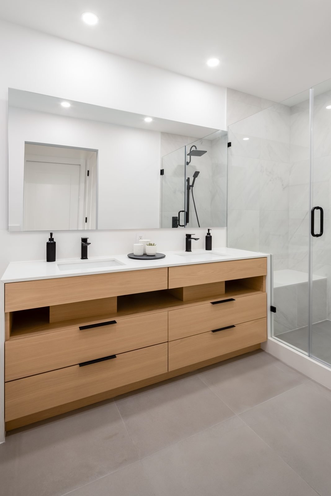 Rift-cut white oak double vanity, white quartz top and frameless glass shower in a Gastown condo ensuite
