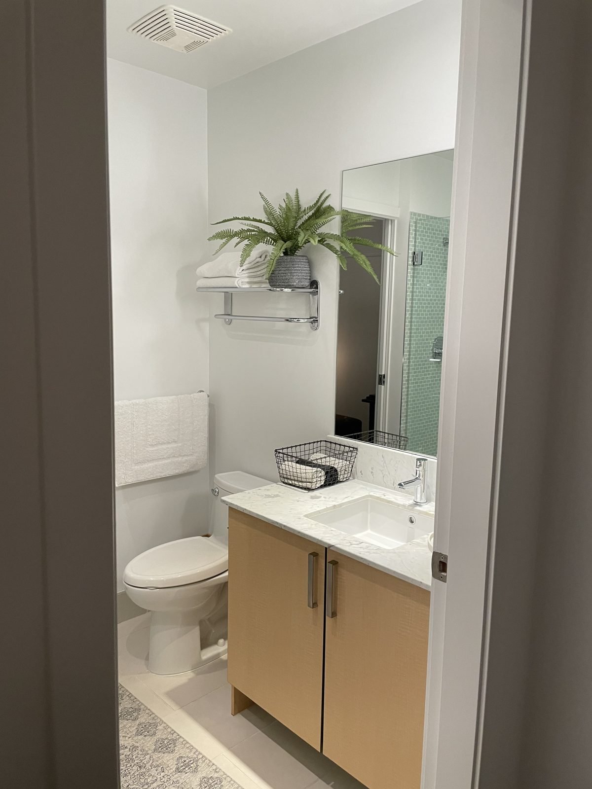 Before: condo main bathroom with a maple vanity and standard toilet in Gastown