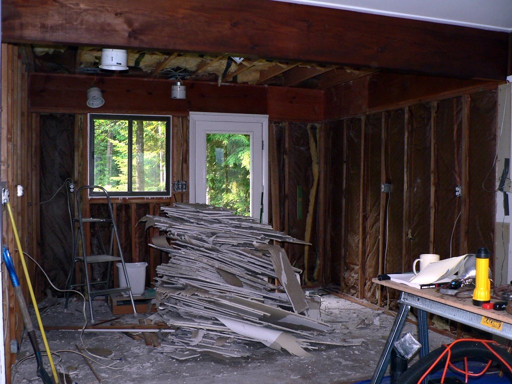 A room stripped back to the studs during a full home renovation, with lumber stacked on the floor