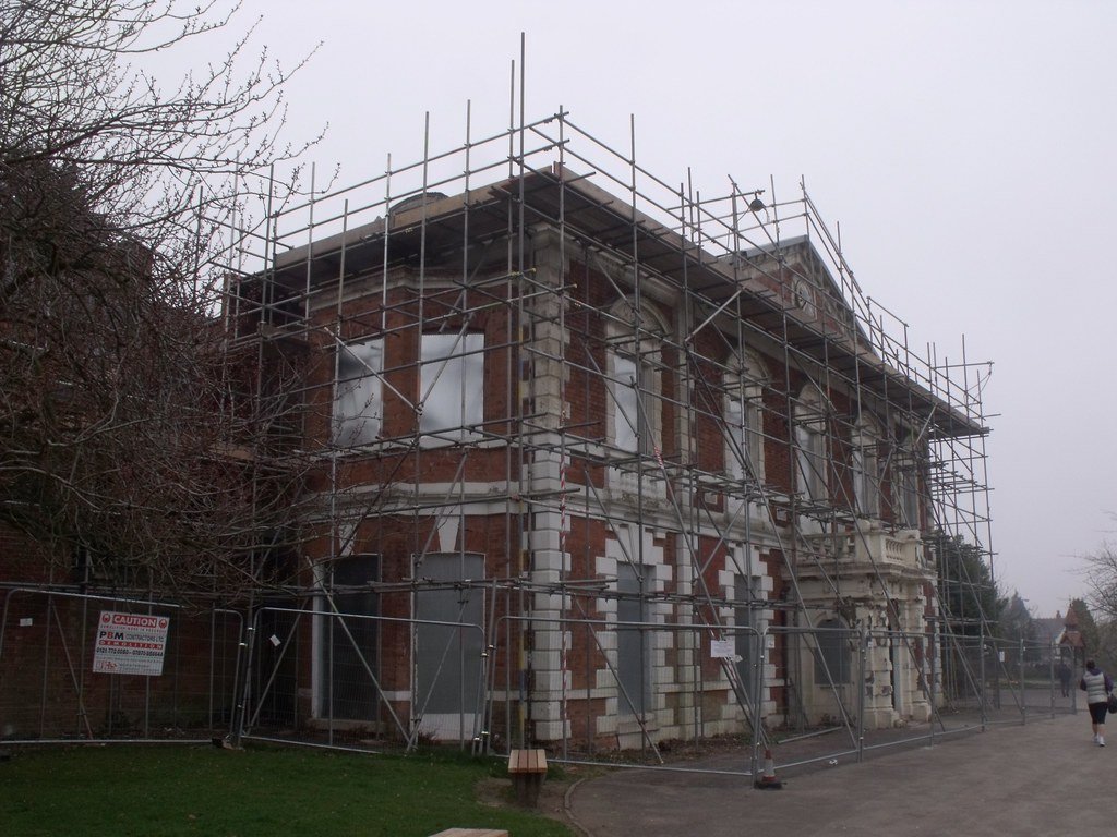 An older brick house wrapped in scaffolding during a major exterior and structural renovation
