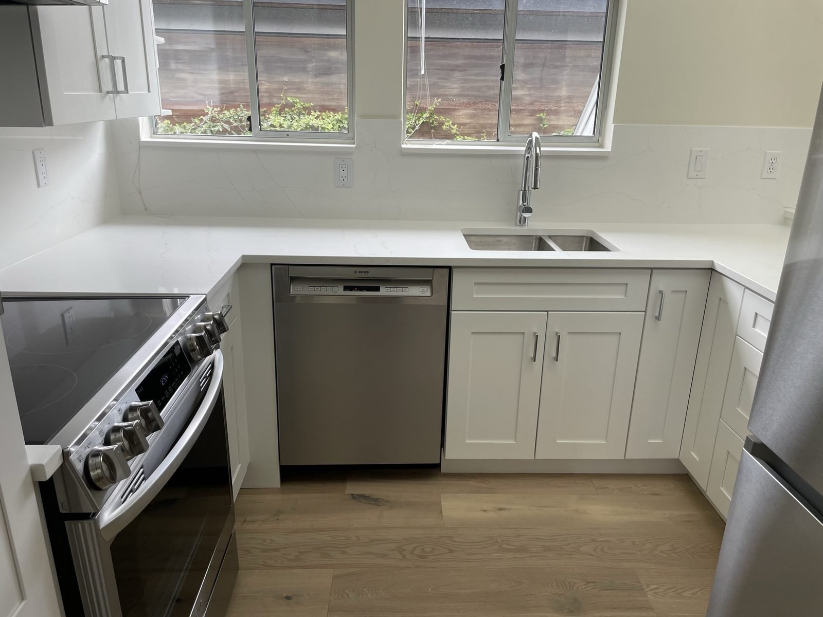 Quartz countertops, stainless dishwasher and white shaker cabinets in a Kitsilano, Vancouver condo kitchen