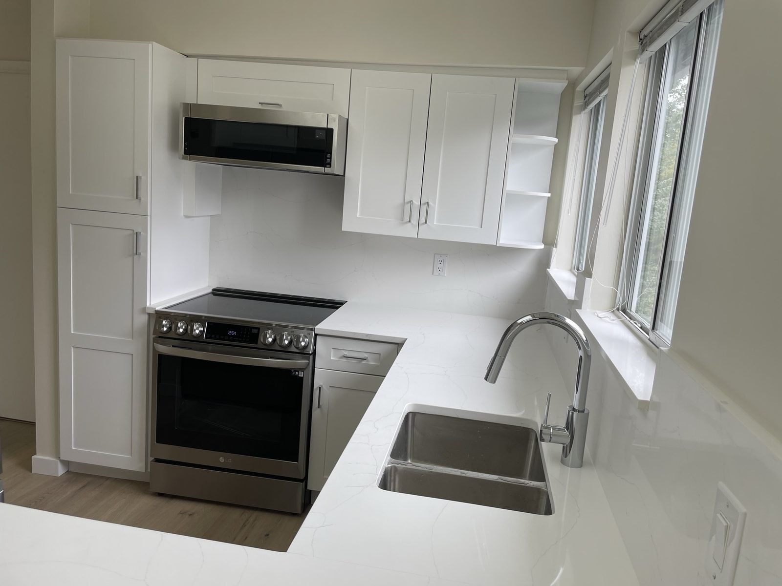 Kitsilano condo kitchen with white shaker cabinets, quartz countertops and stainless appliances