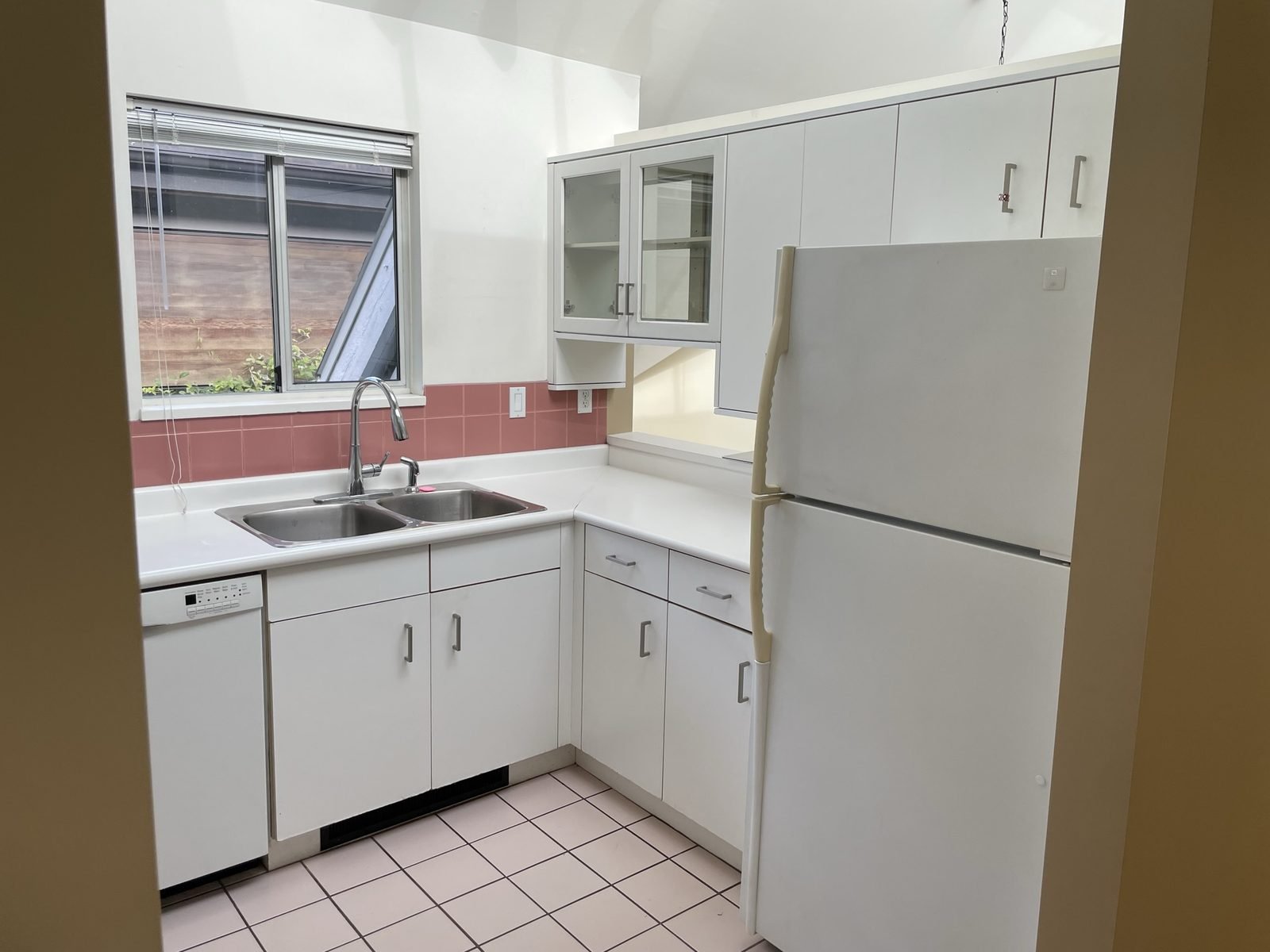 Before: dated condo kitchen with a white fridge and laminate cabinets in Kitsilano