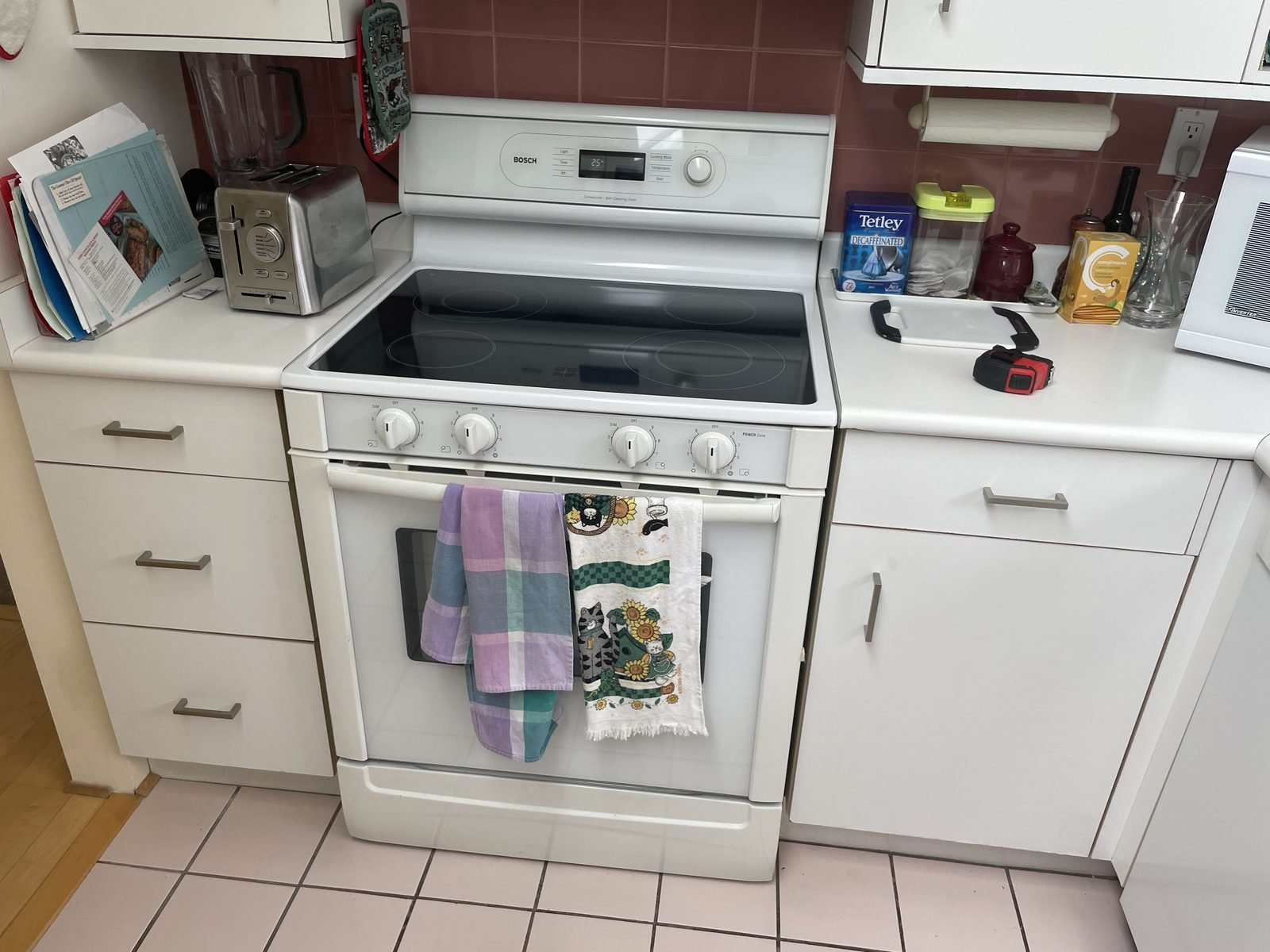 Before: white laminate cabinets, mauve tile backsplash and a white range in a Kitsilano condo kitchen
