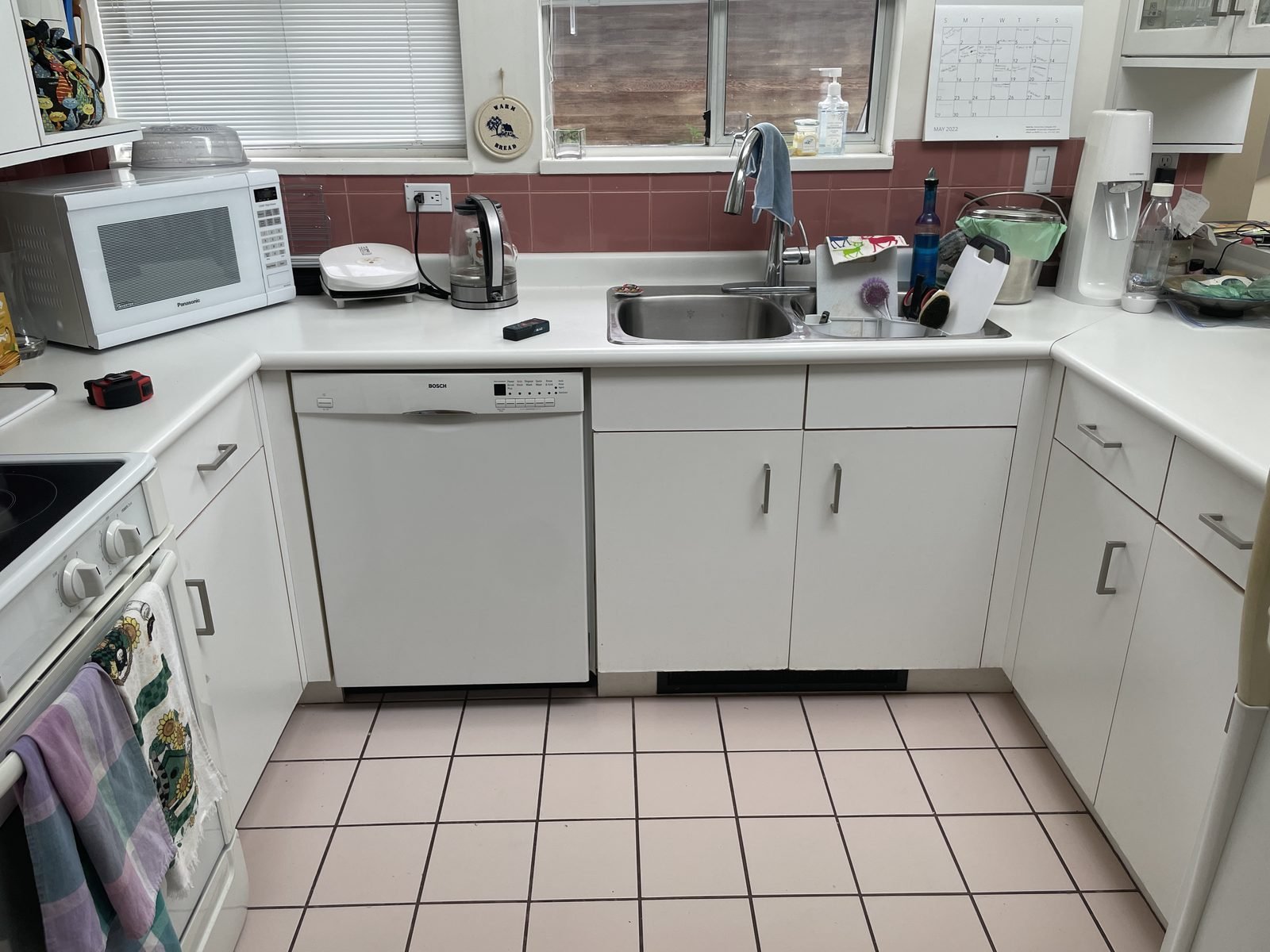 Before: U-shaped condo kitchen with pink floor tile and white appliances in Kitsilano, Vancouver