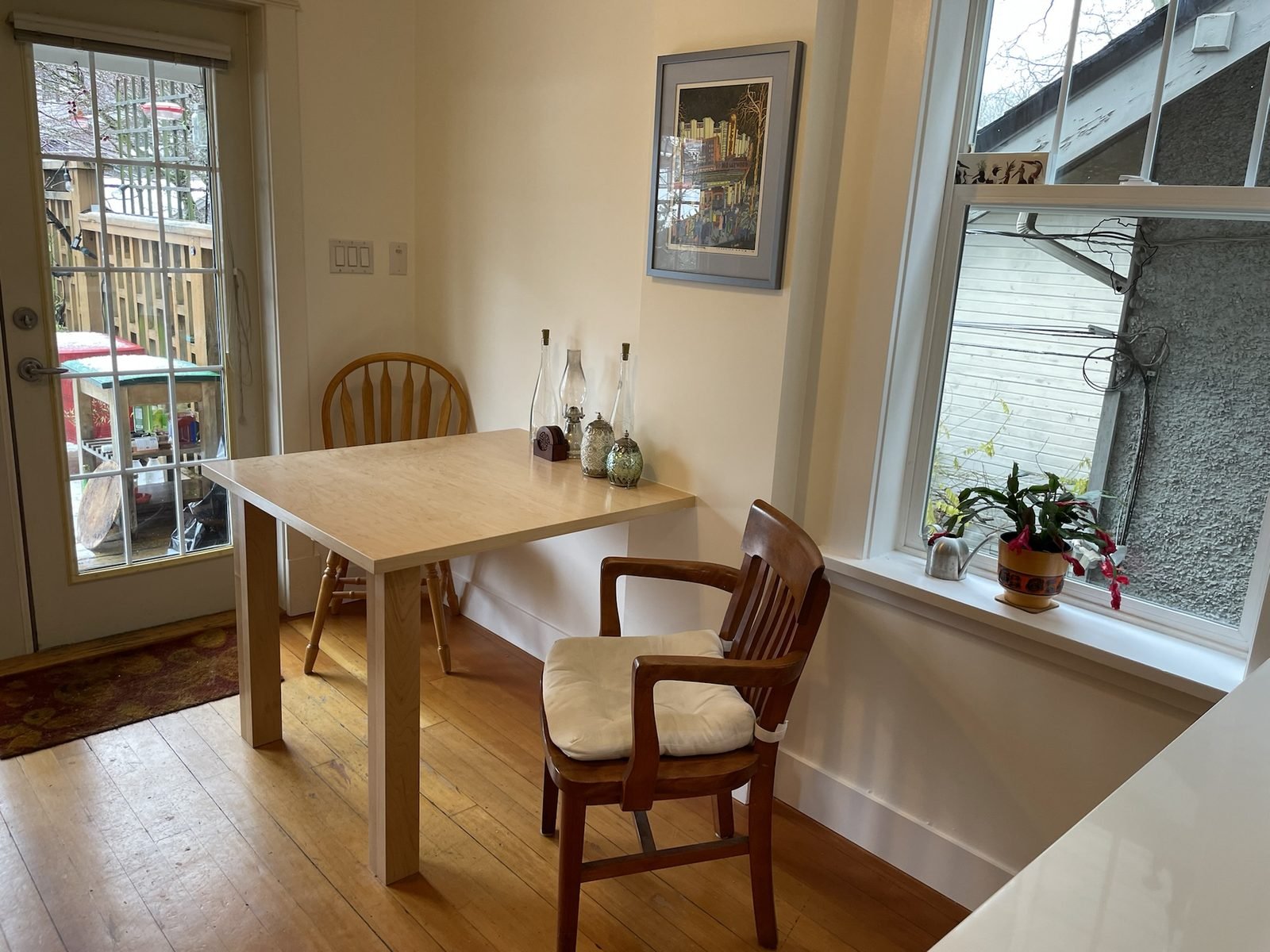 Custom maple dining table by the window beside a renovated Kitsilano kitchen