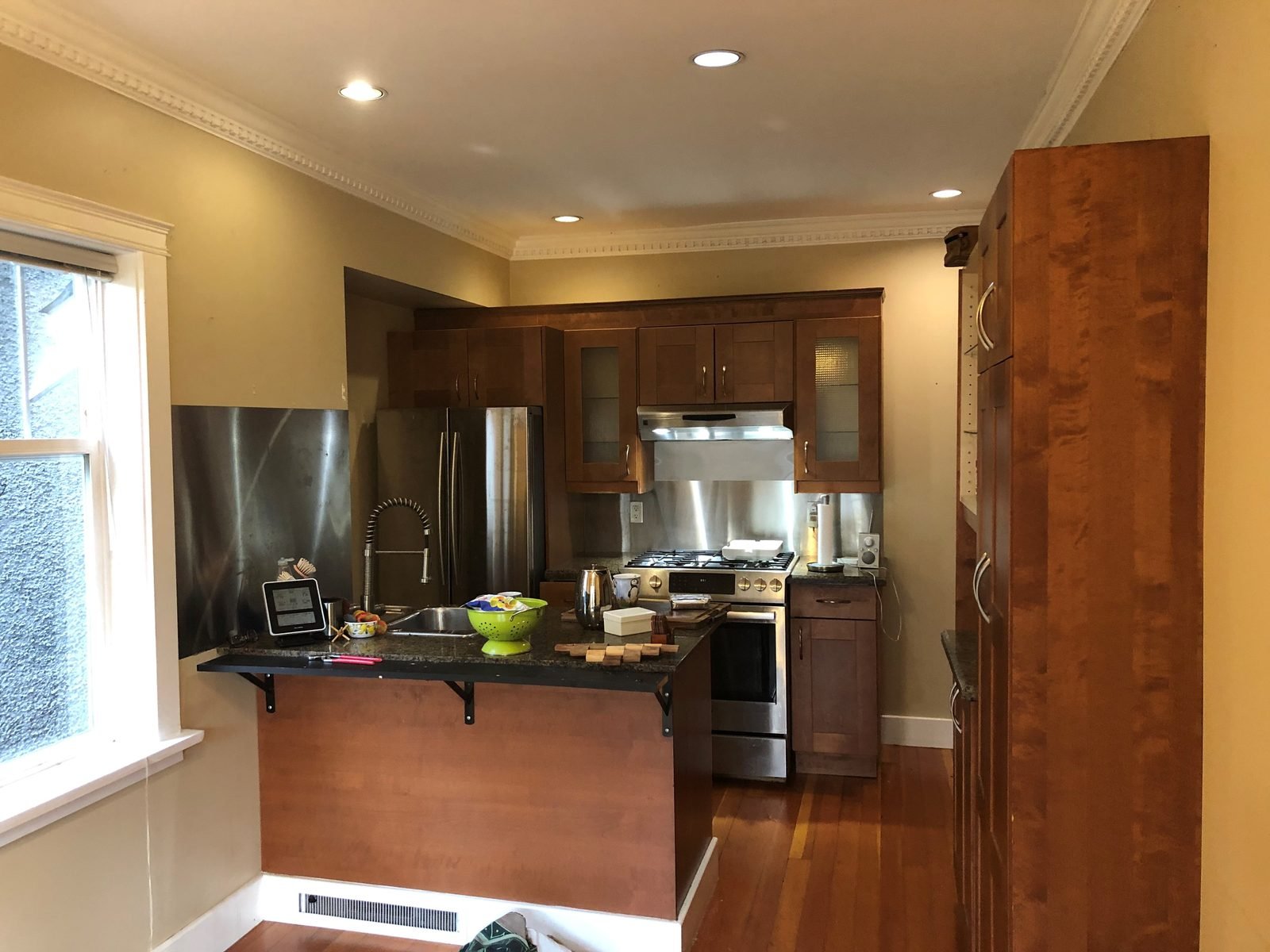 Before: dark wood kitchen with a raised granite peninsula in a Kitsilano home