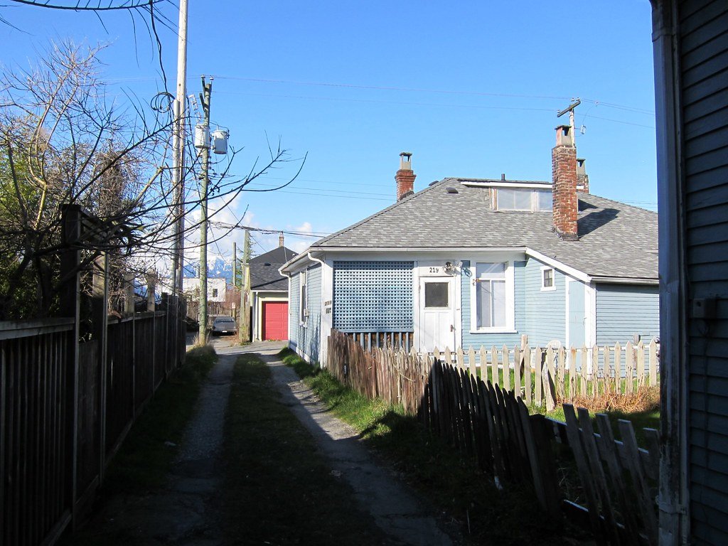 A small house facing a back lane, the kind of lot where laneway homes are built