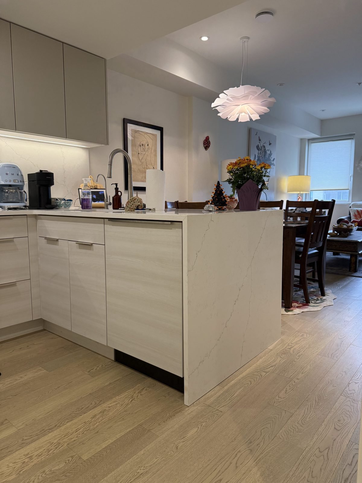 Side view of the white quartz waterfall peninsula and pendant light in a renovated North Vancouver kitchen