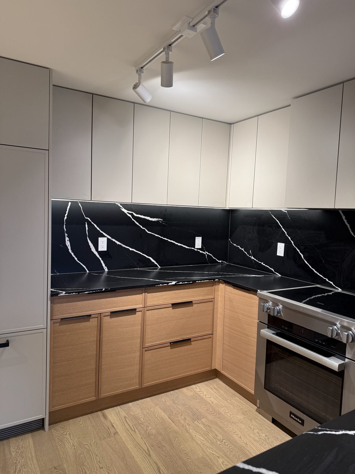 Before: black quartz countertops and full-height black backsplash on the range wall of a North Vancouver kitchen