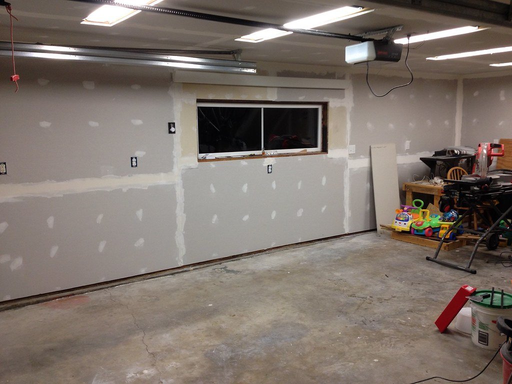 A room with new drywall on the walls and ceiling, taped and ready for finishing
