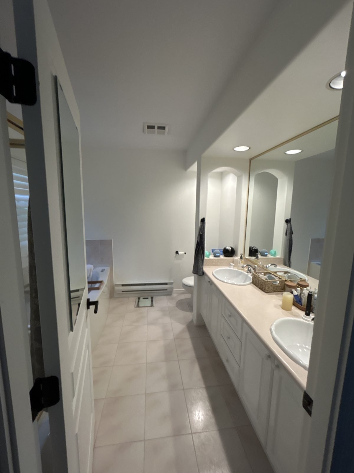 Before: dated ensuite with a white cabinet vanity and large wall mirror in a North Vancouver townhouse