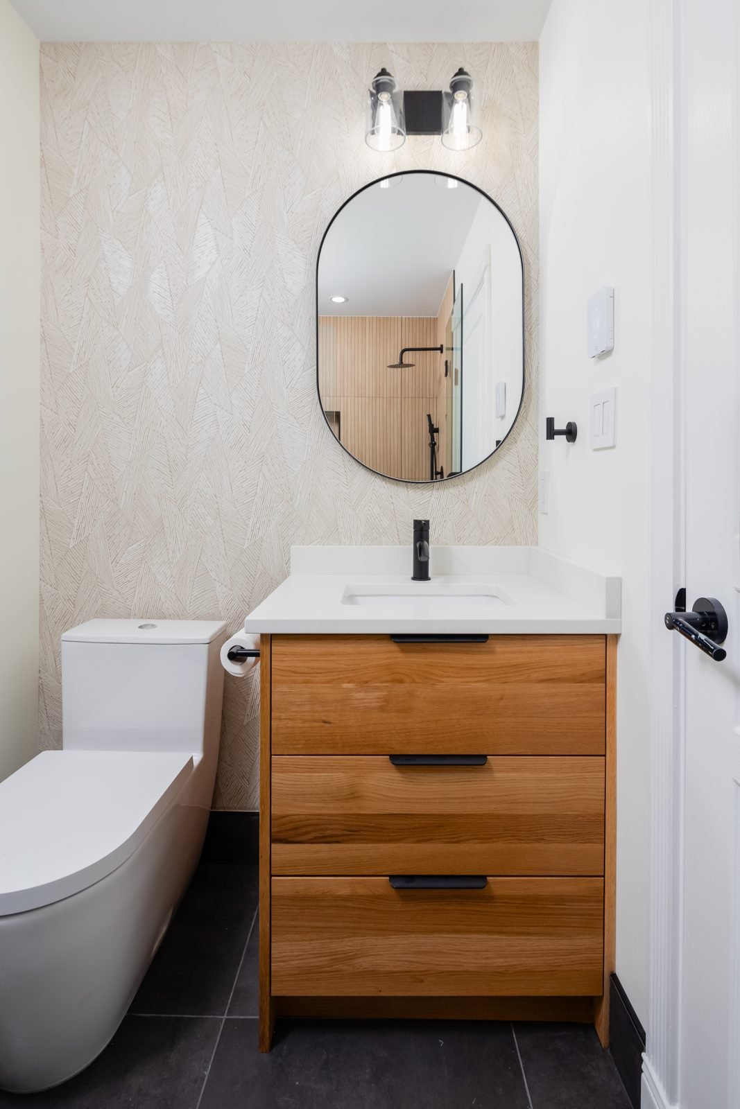 North Vancouver main bathroom renovation with textured wallpaper, wood vanity and dark floor tile