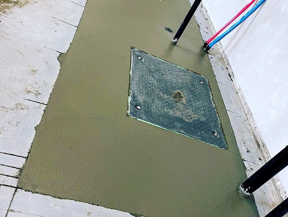 New concrete patch around a floor drain after the plumbing trench was filled