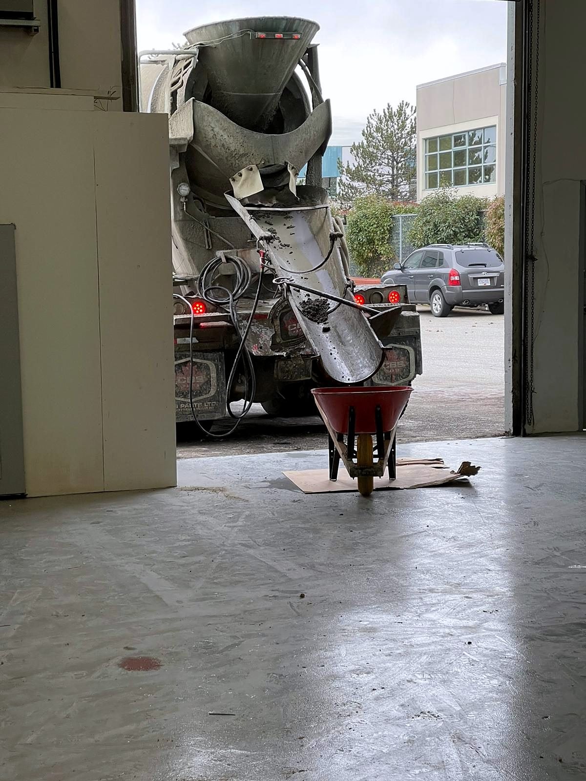 Concrete being poured to fill plumbing trenches in the warehouse floor