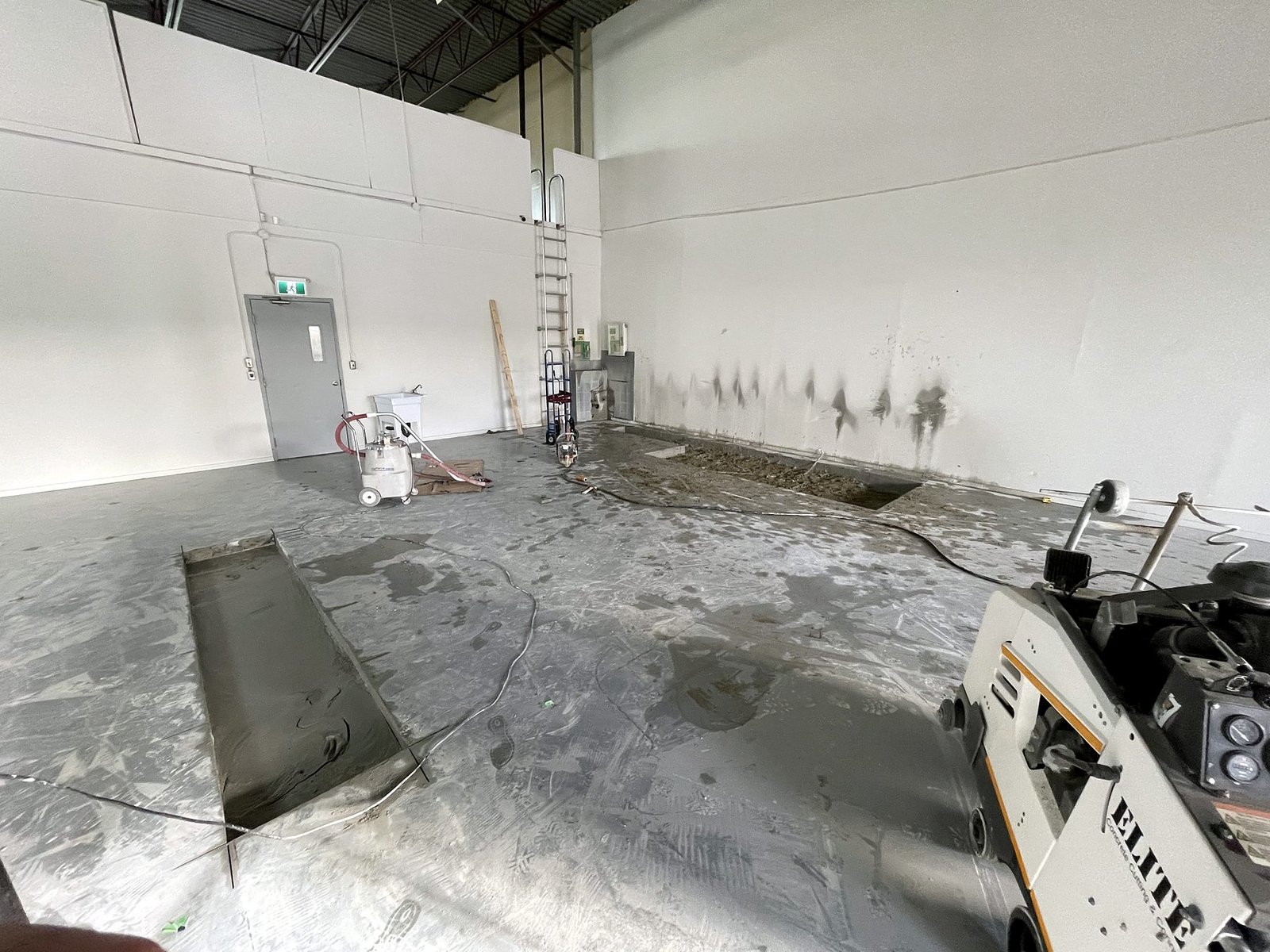 Concrete slab saw-cut for a new under-slab plumbing trench in a Delta warehouse