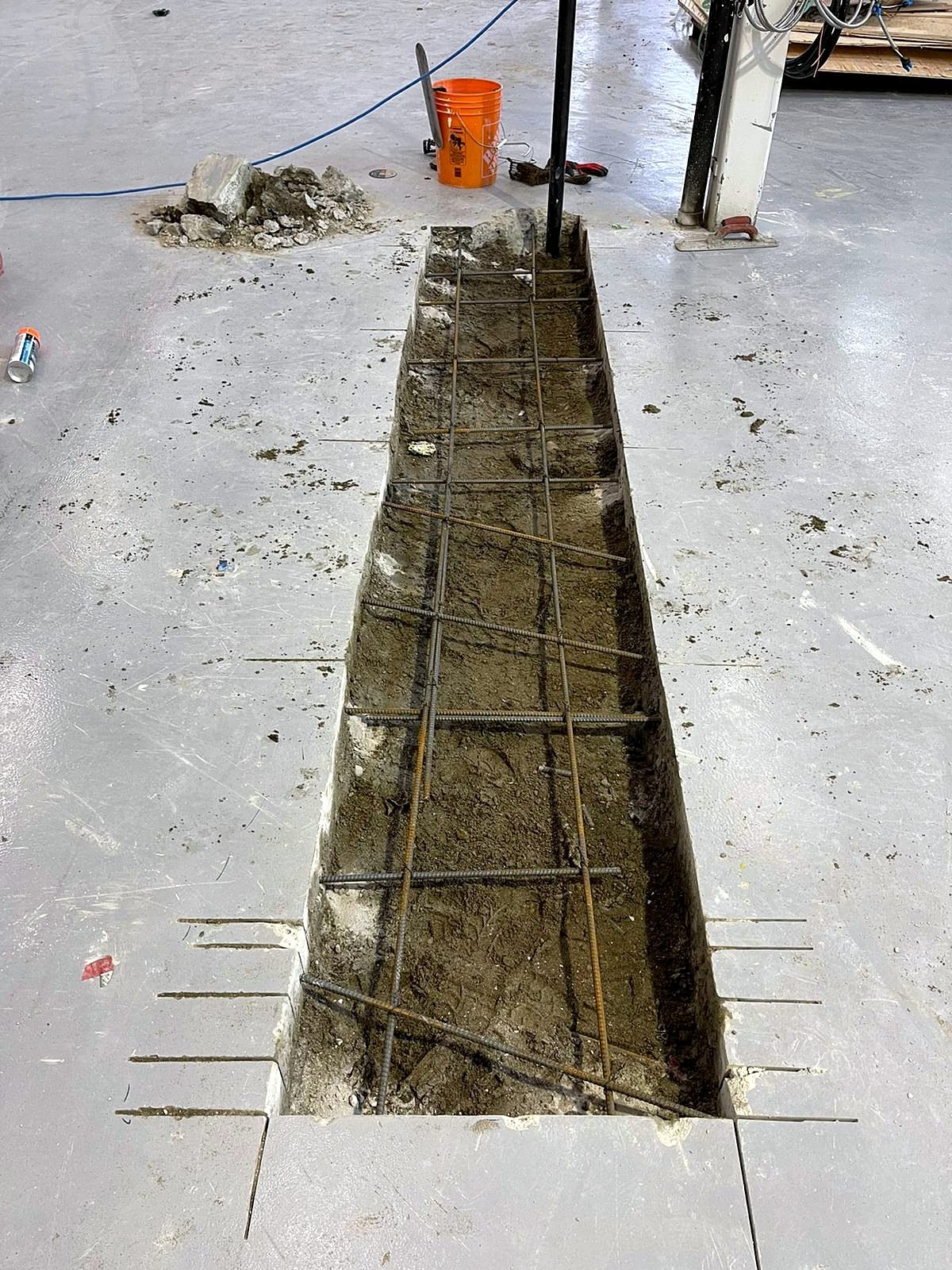 Open plumbing trench with dowels drilled into the existing concrete slab