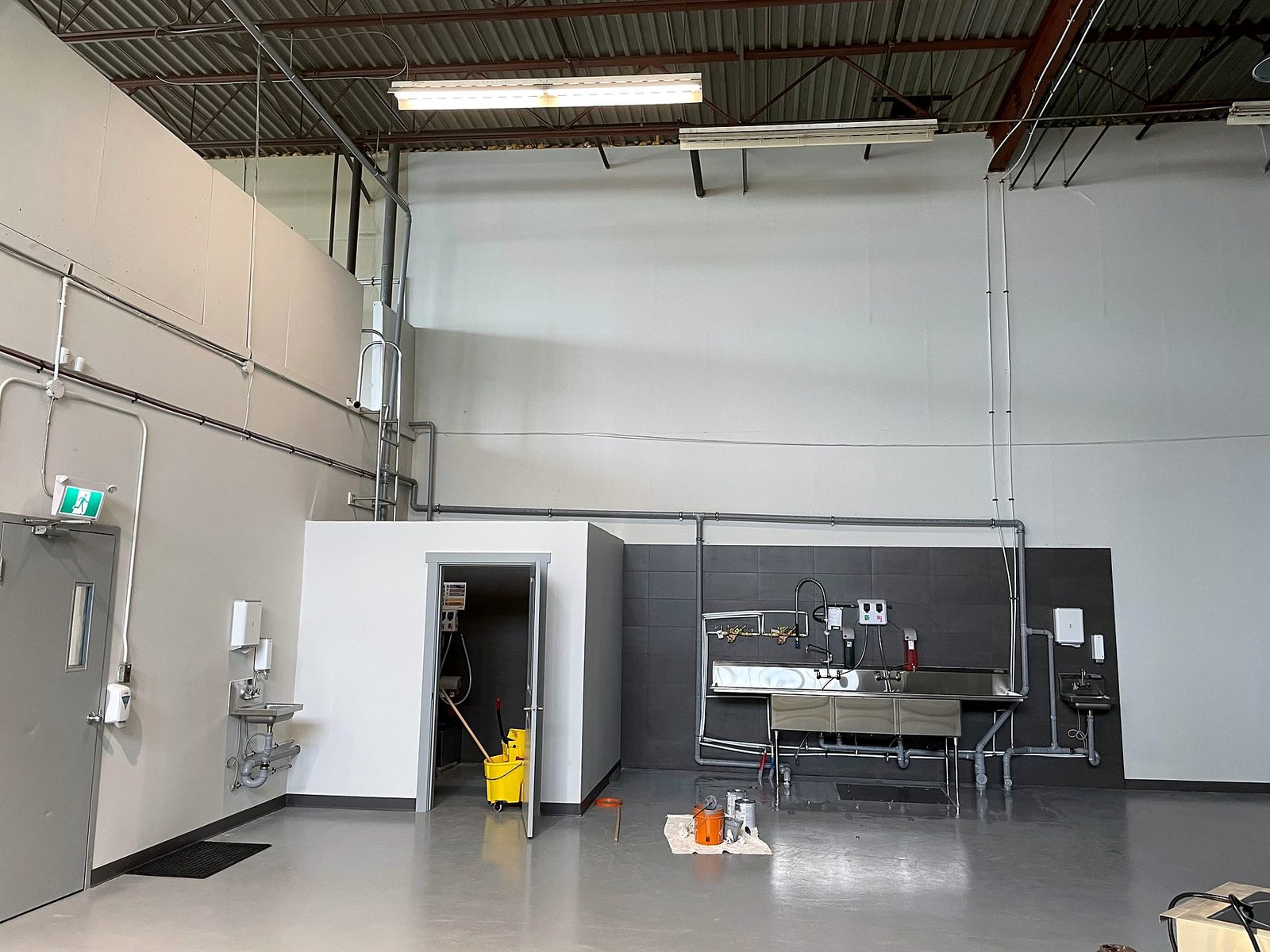 Three-compartment stainless sink with tiled backsplash, hand sinks and new janitor room in the NutJar warehouse in Delta