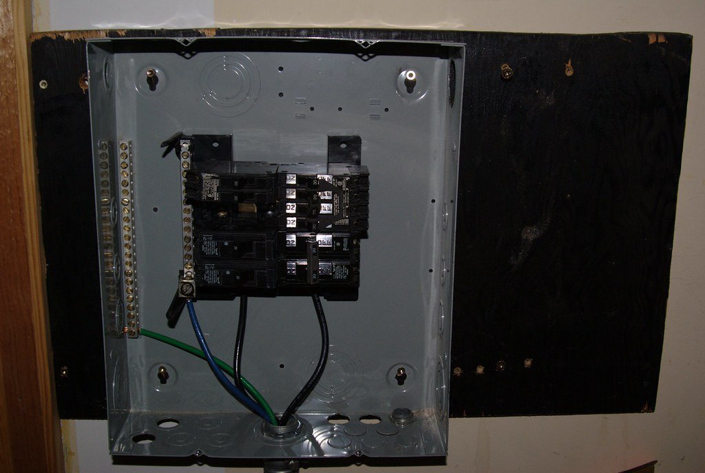 An open residential electrical breaker panel with its cover removed, showing breakers and wiring