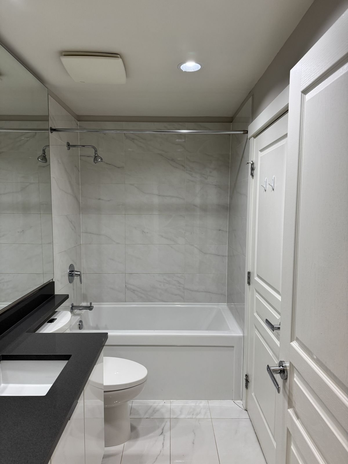 Before: Richmond condo bathroom with a standard tub, shower curtain rod and builder finishes