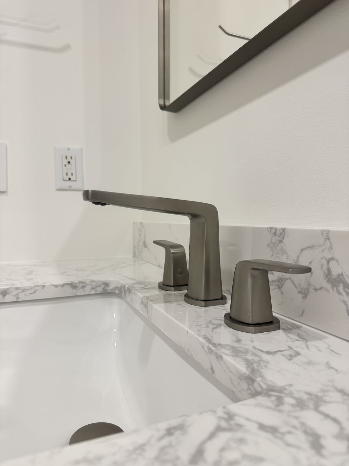 Brushed nickel widespread faucet on a marble-look vanity top with an undermount sink in a Richmond condo