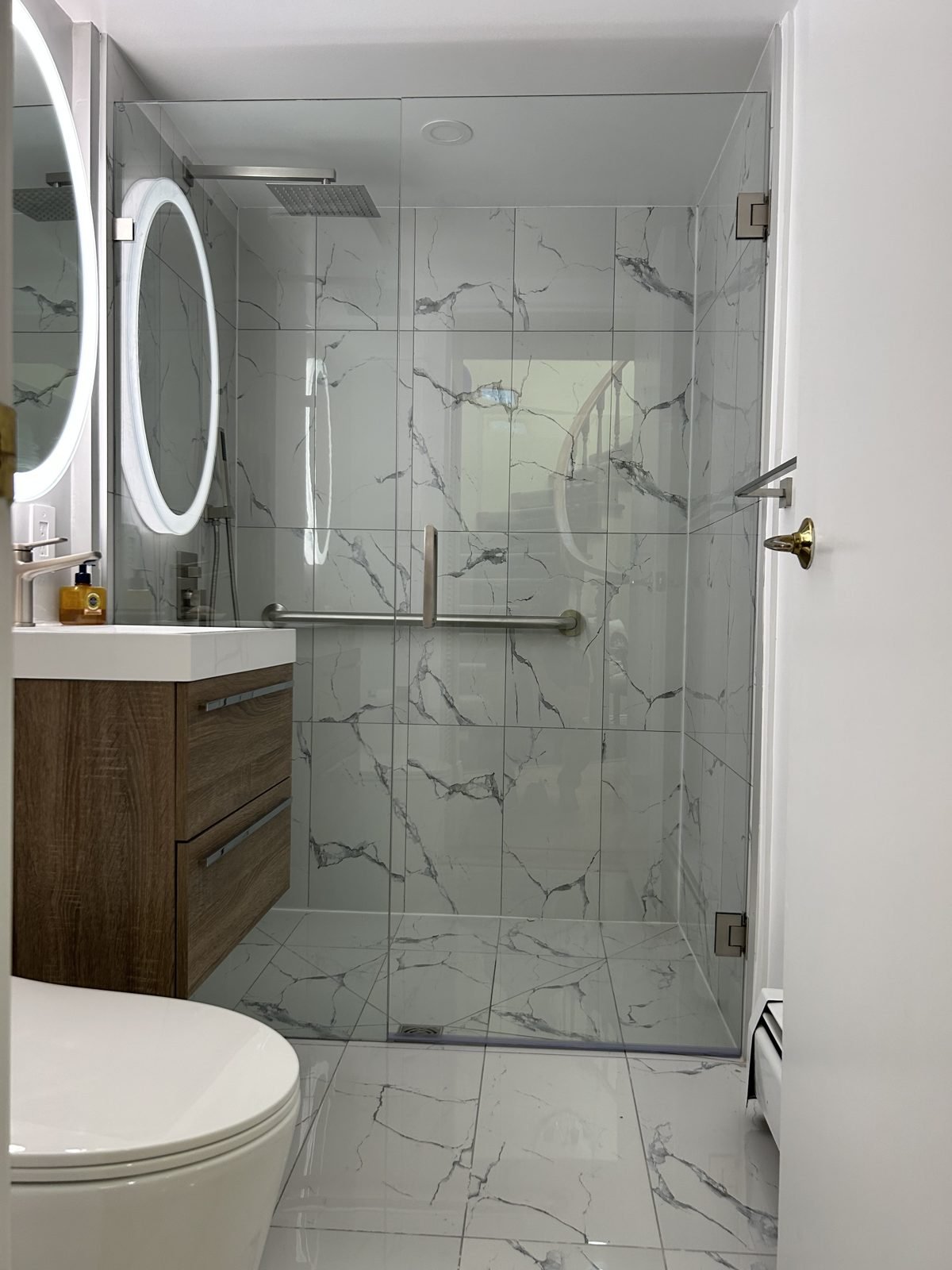 Frameless glass door on a curbless walk-in shower with marble-look tile in a new Shaughnessy bathroom