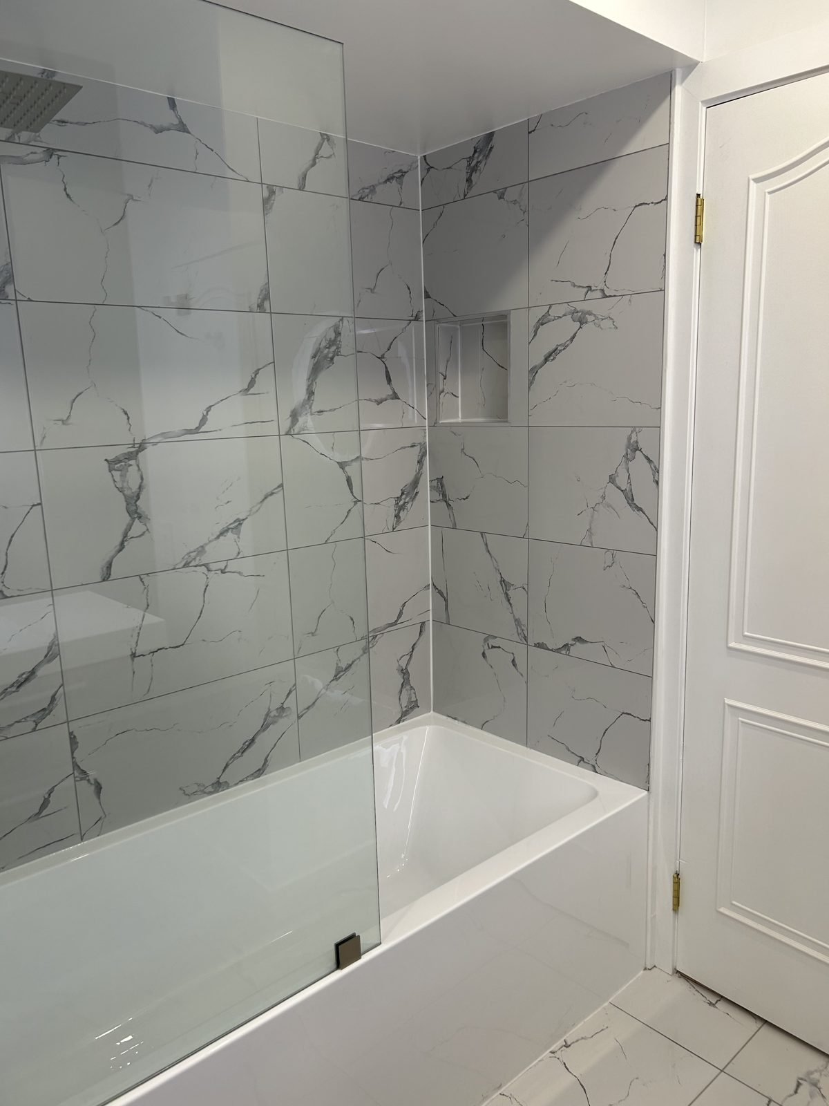 Recessed shower niche in marble-look tile above a new tub in a Shaughnessy main bathroom