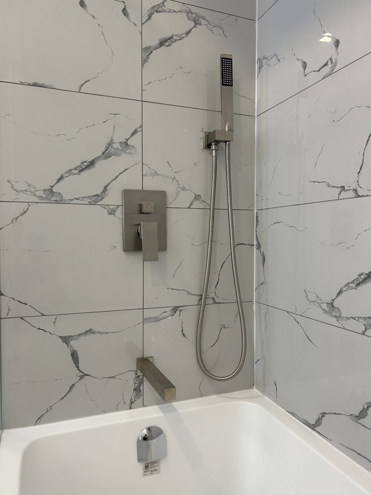 Brushed tub spout, shower valve and hand shower over a new bathtub in a Shaughnessy main bathroom