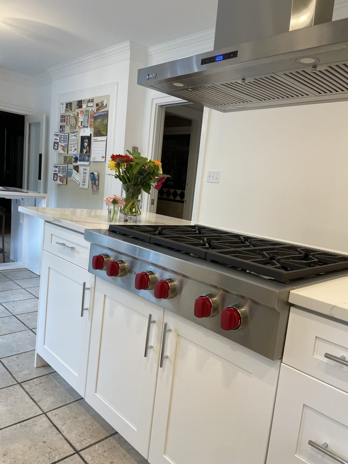 Gas rangetop and stainless hood over a white shaker island in a Shaughnessy, Vancouver kitchen