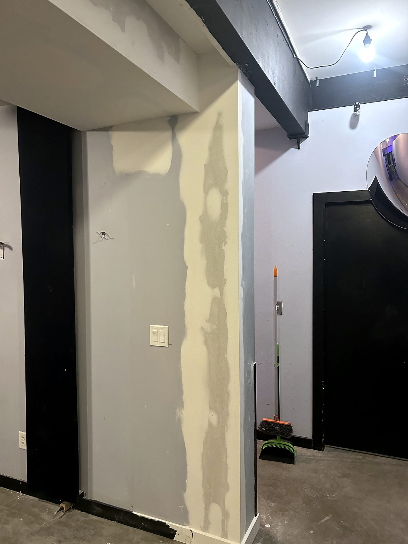 Drywall patched and prepared for paint at the bulkhead where the studio wall was removed, with relocated light switch