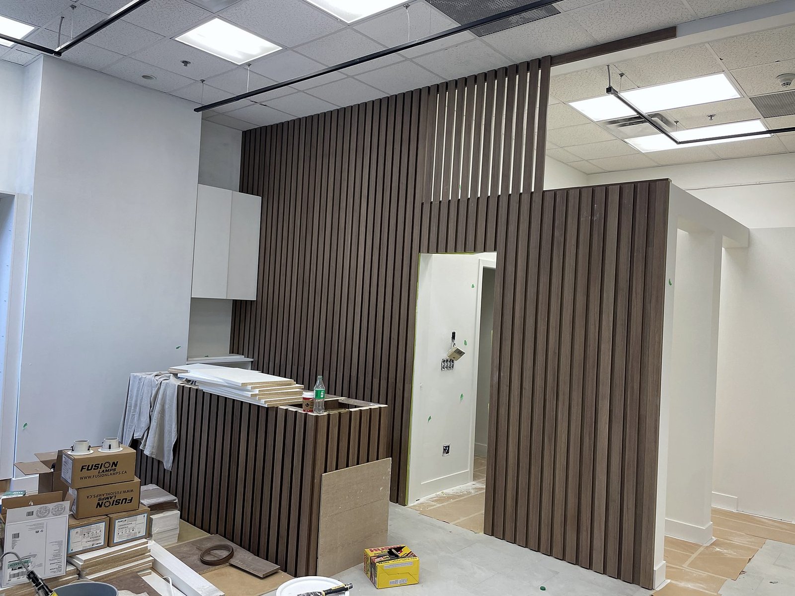 Wood slat wall and cash desk millwork being installed during construction