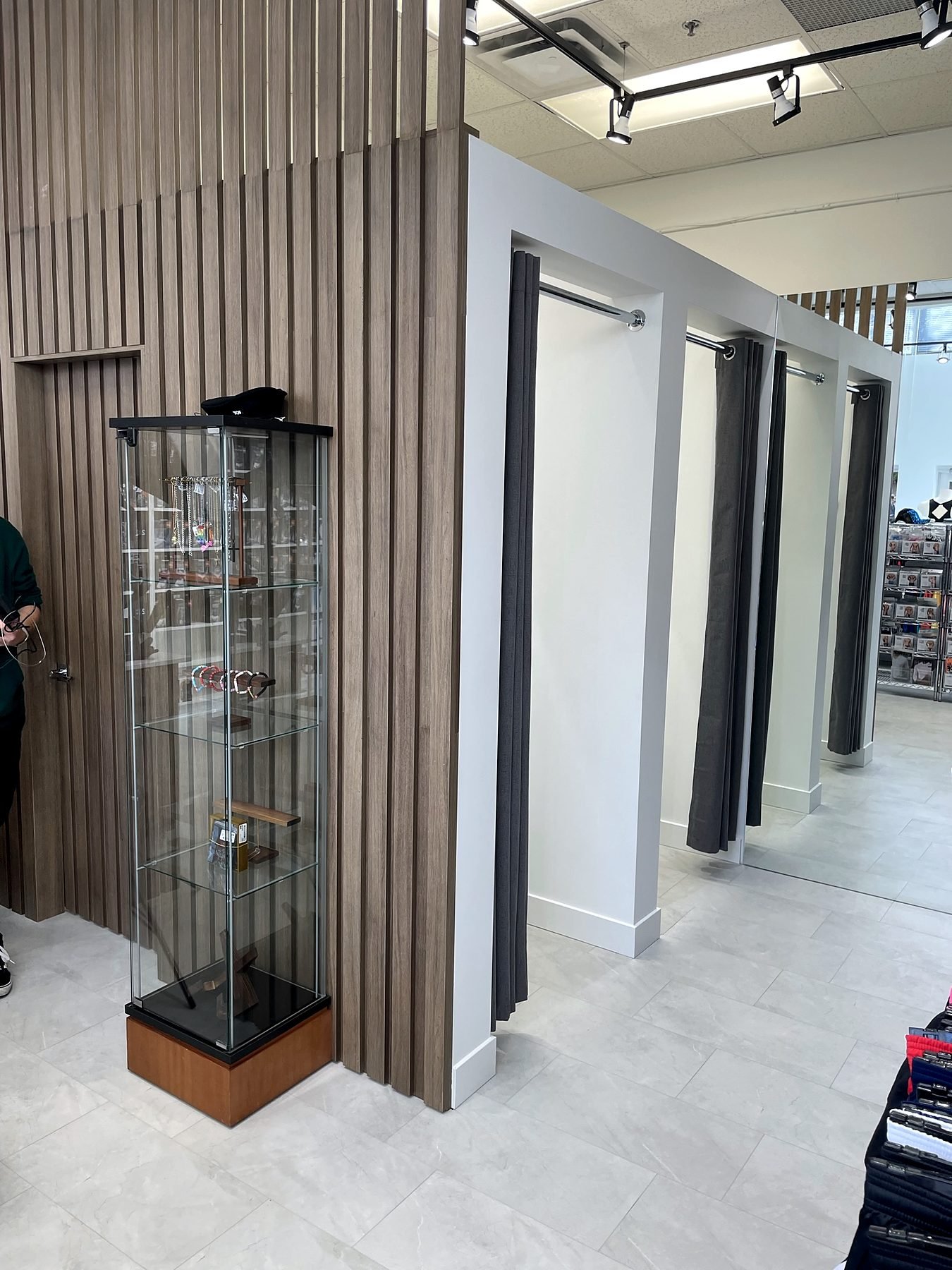 Wood slat wall beside the fitting rooms with a glass display case