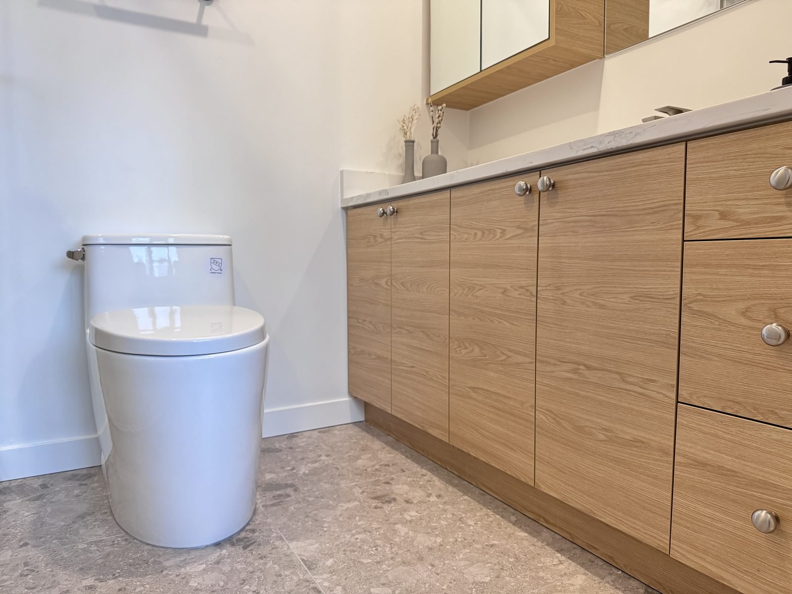 One-piece toilet beside a long wood-grain vanity with a quartz top in a West End condo ensuite