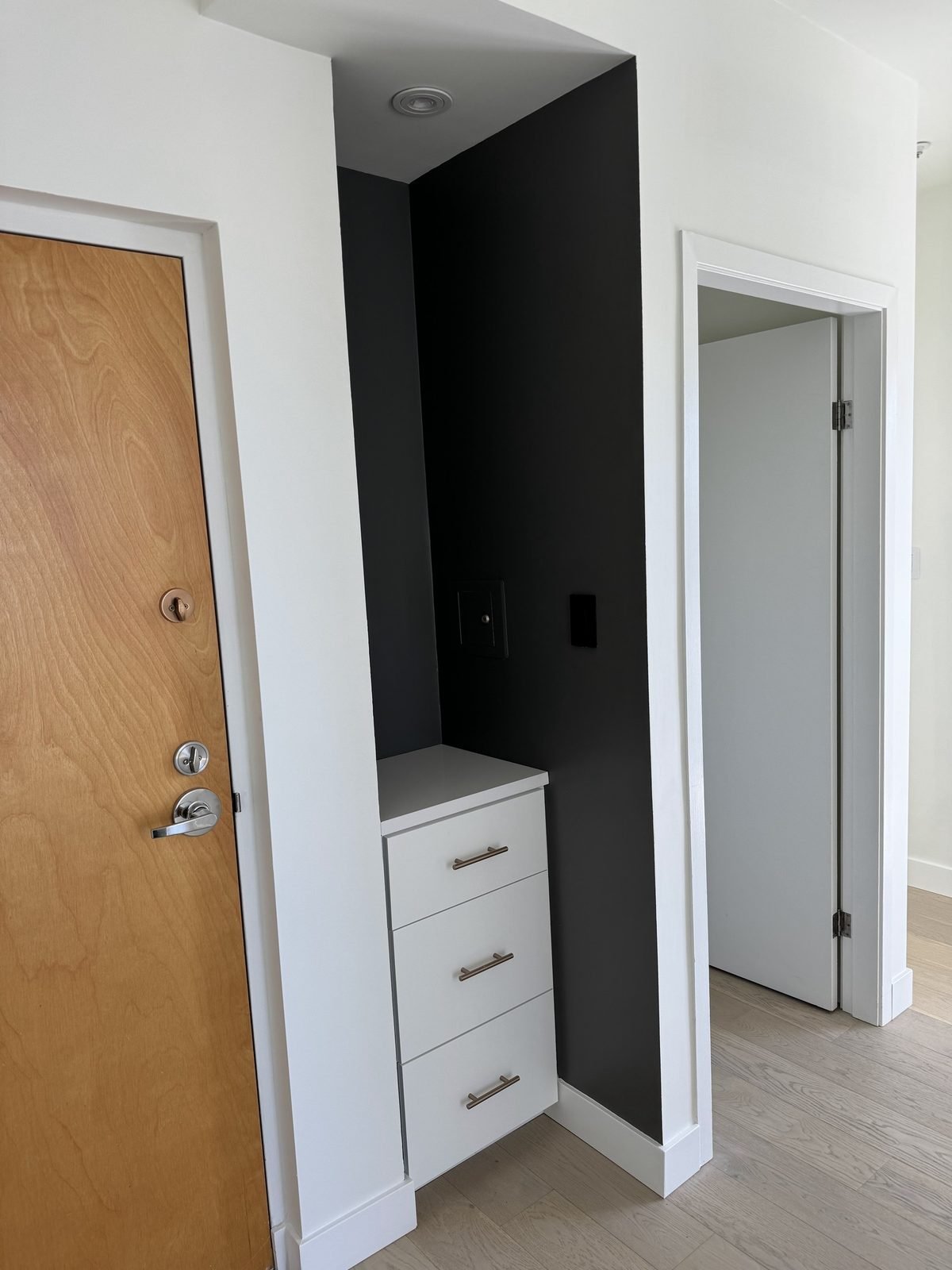 Entry with a black accent wall, built-in drawers and lighting in a renovated West End condo