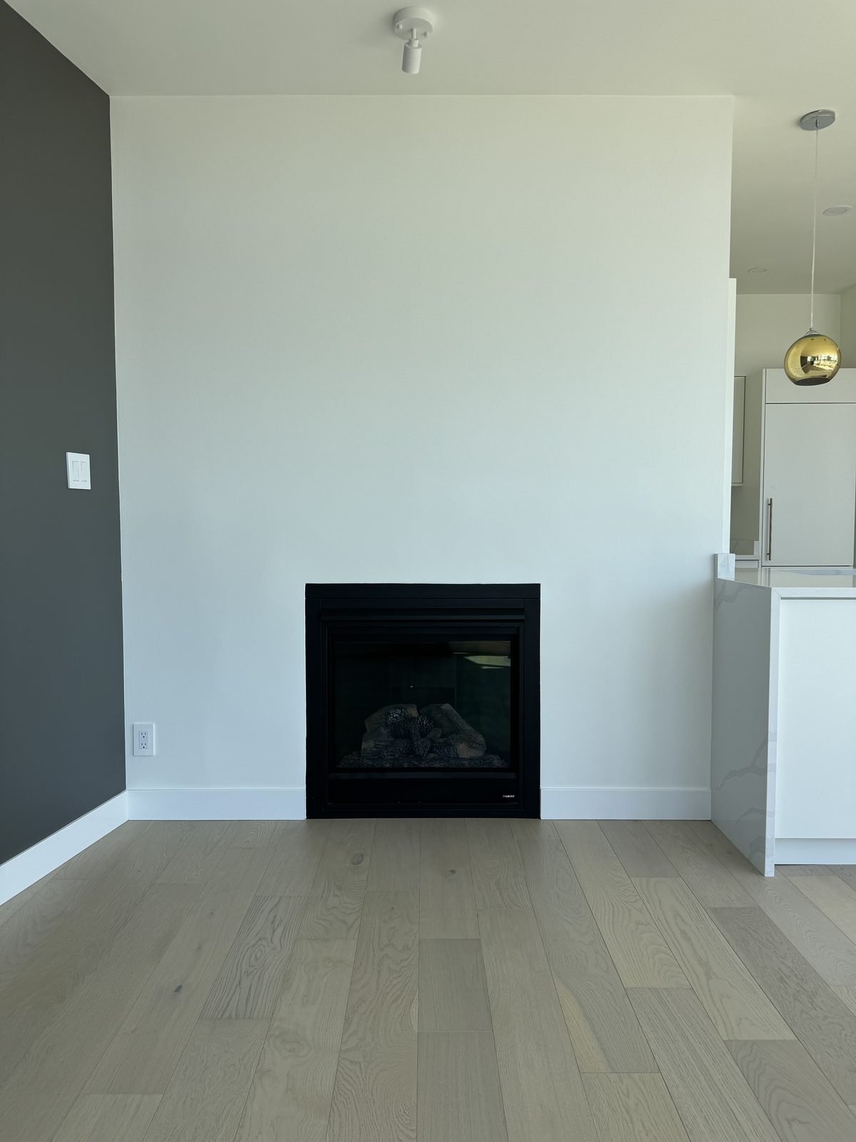 After: living room with a new fireplace insert, smooth drywall surround and light engineered hardwood in a West End condo