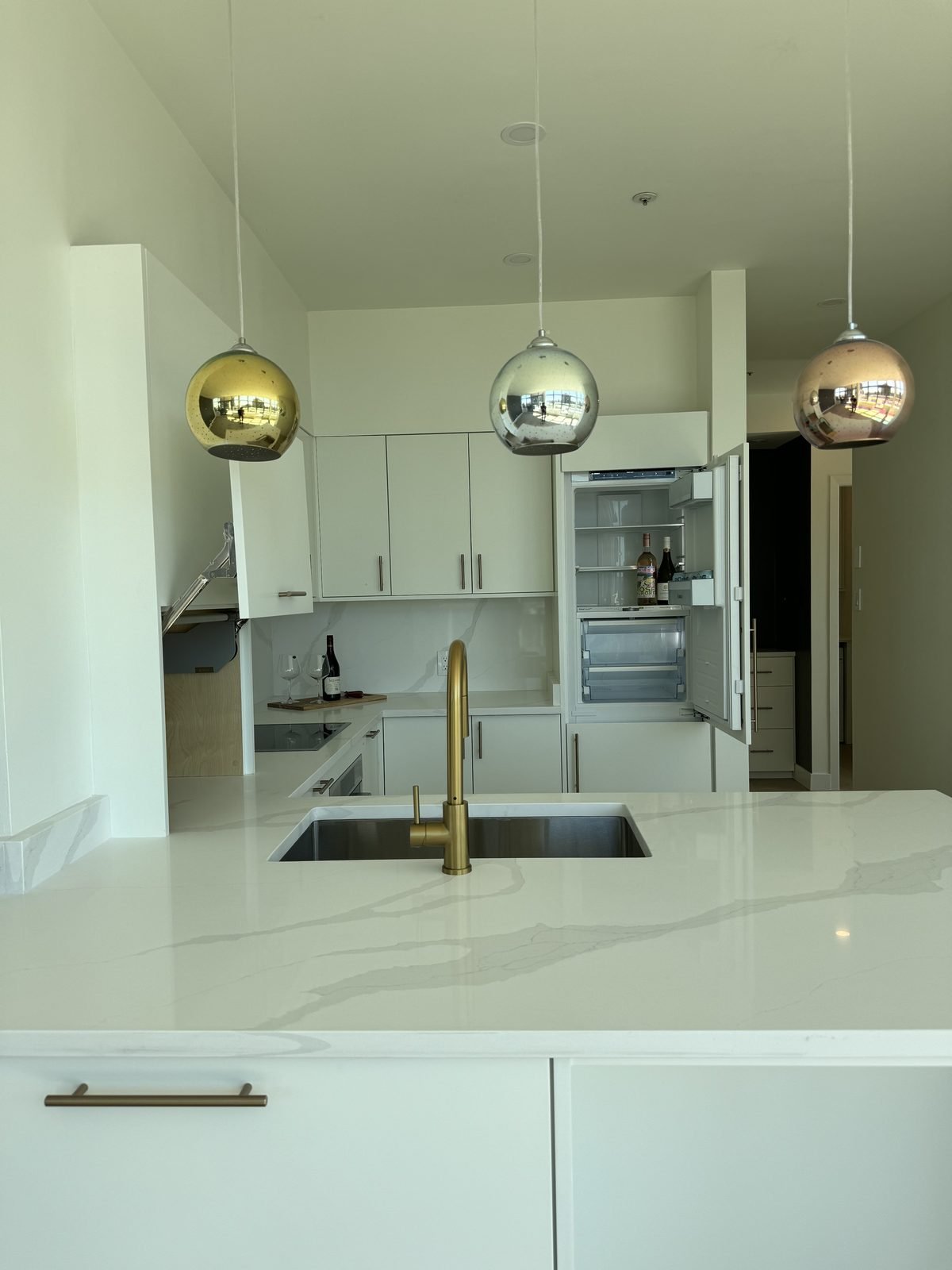 Panel-ready fridge column and brass faucet over an undermount sink in a West End condo kitchen